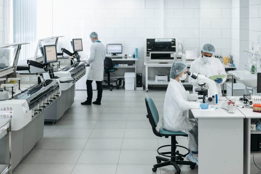 Free Researchers in lab coats performing experiments with advanced equipment in a laboratory. Stock Photo
